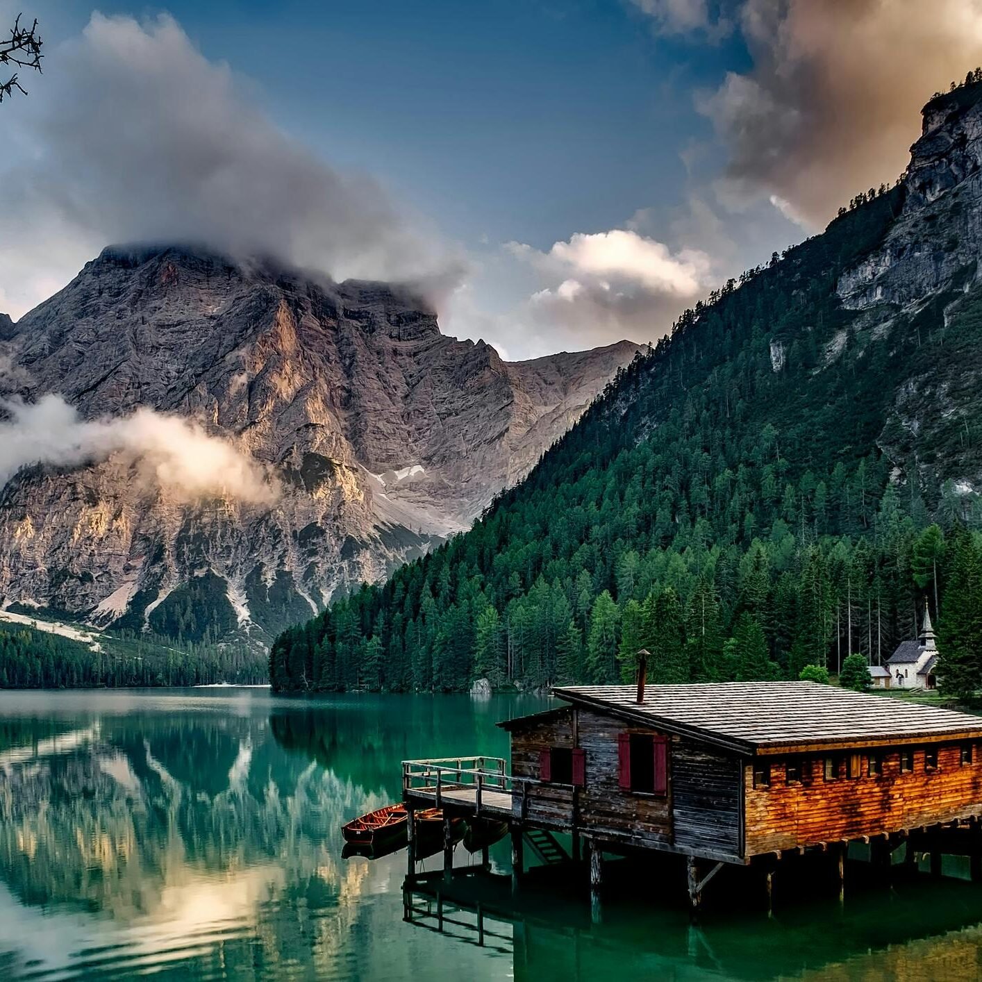 Peaceful mountain lake scene featuring a rustic boathouse and stunning reflections.