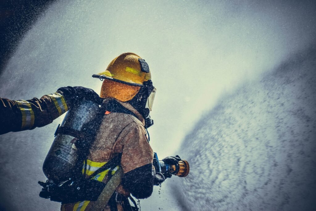 pexels-photo-2030190-2030190 A brave firefighter in protective gear sprays water during training or emergency.