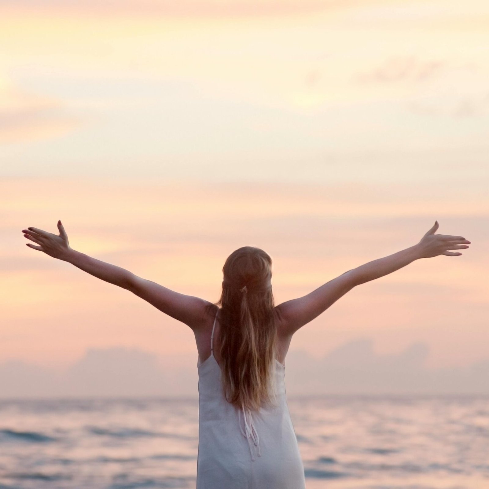 A woman enjoying a serene sunset on Unawatuna Beach, Sri Lanka, depicting peace and freedom.