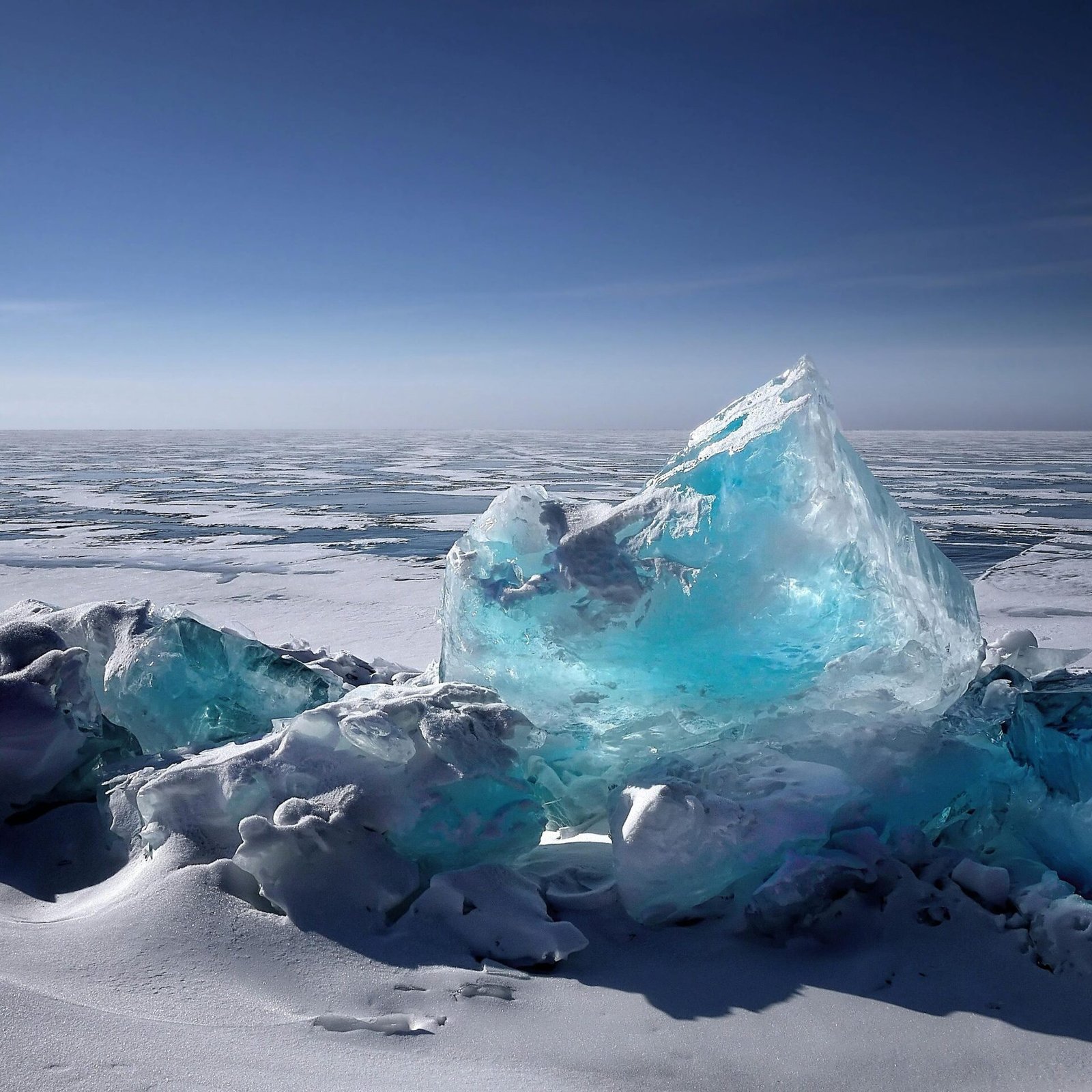 Captivating ice formation on a frozen lake under a bright blue sky during winter.