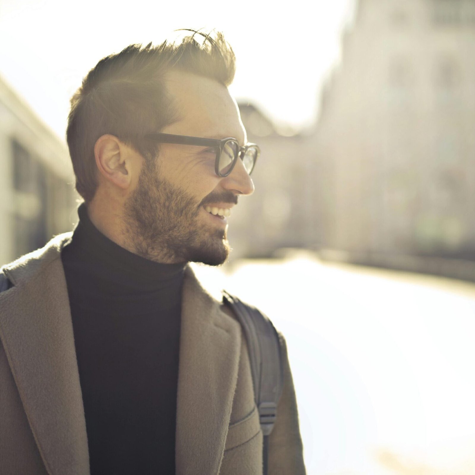 Smiling man with glasses and coat enjoying a sunny day in Budapest.